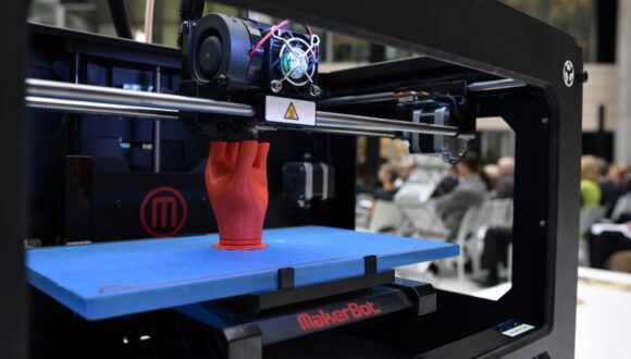 3D printer printing out a red human hand.